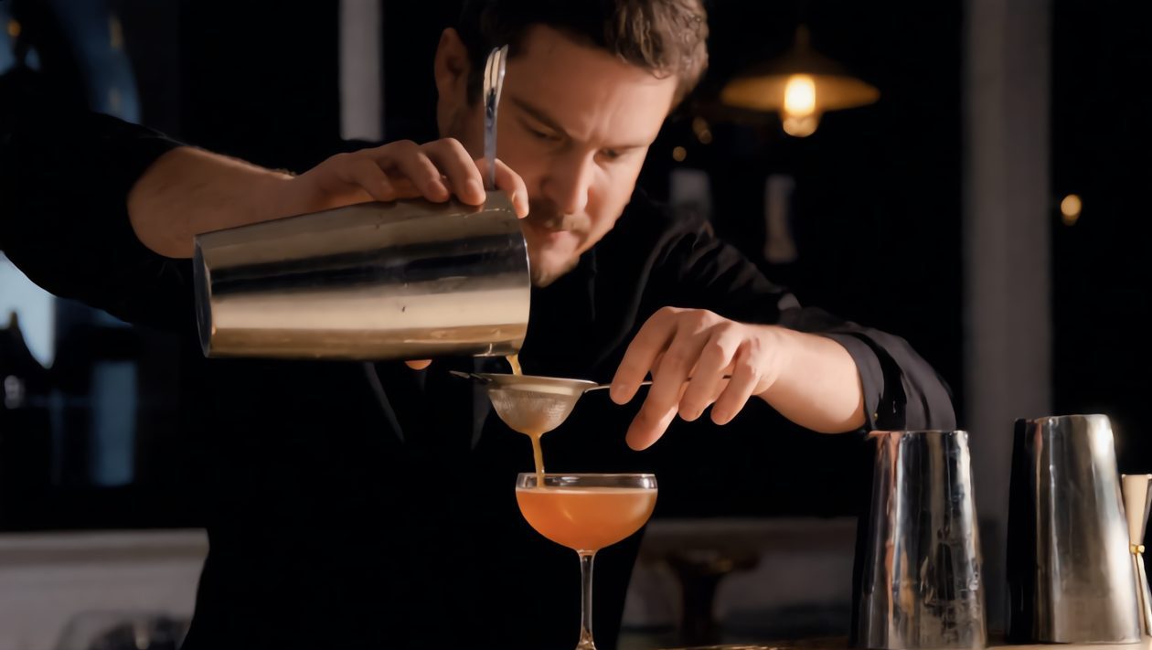 Barkeeper gießt einen Cocktail ab