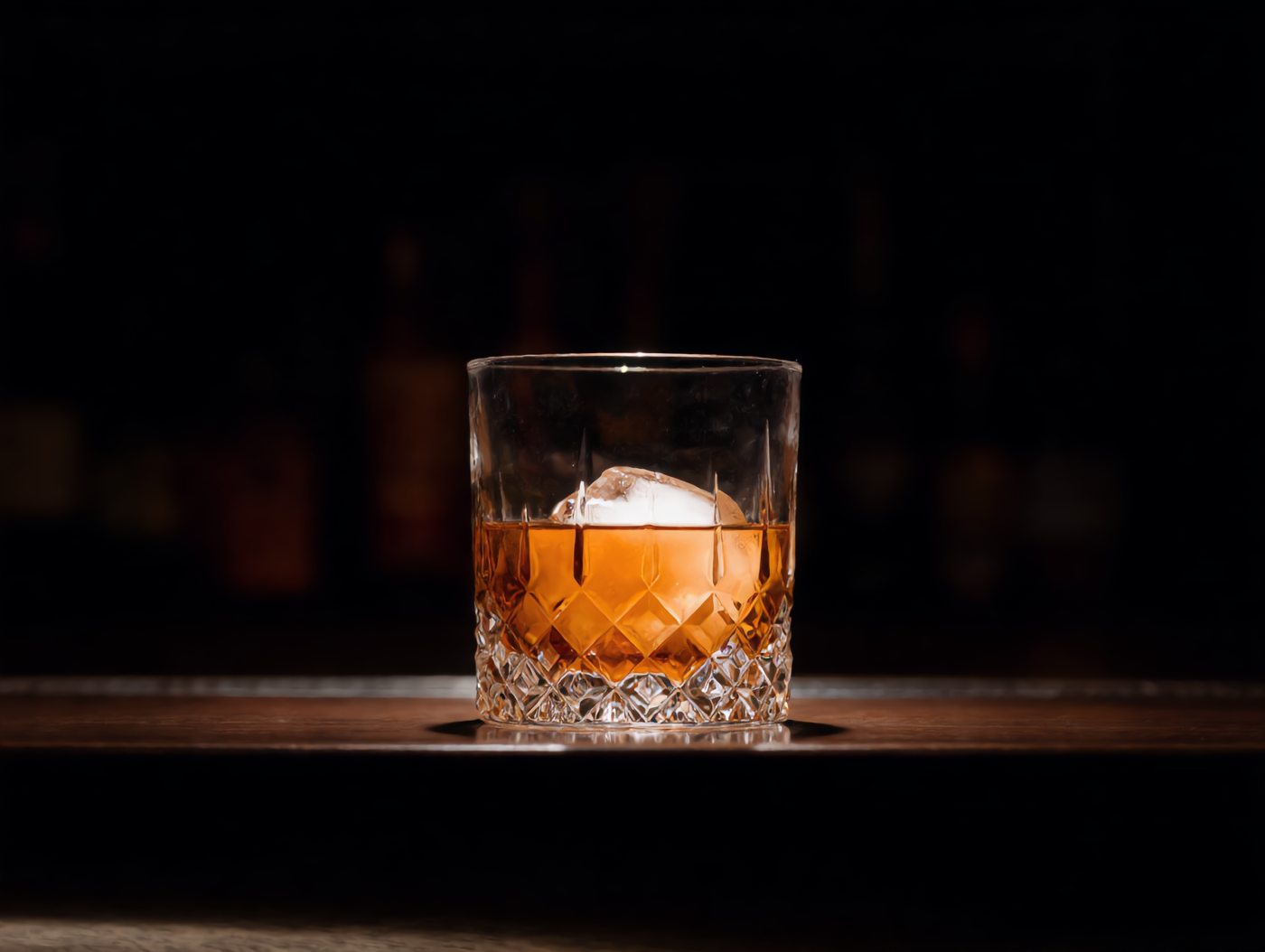 Bernsteinfarbener Cocktail mit großem Eiswürfel